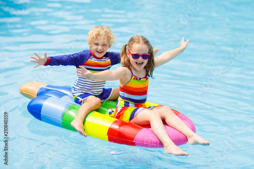 Kids on inflatable float in swimming pool.