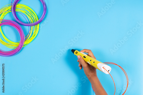 Child draws with 3d pen. Kid holding 3d pen with plastic filament photo