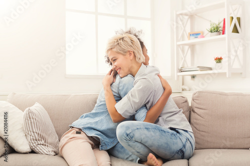 Two young female friends hugging at home