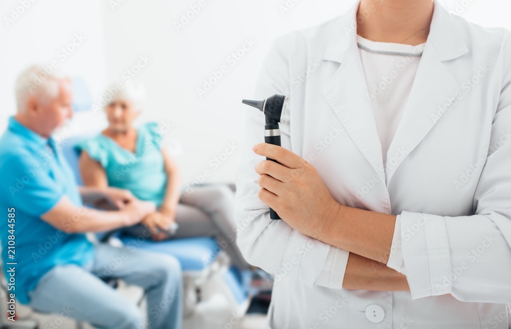 smiling doctor standing before elderly patients in medical office smiling doctor standing before elderly patients in medical office