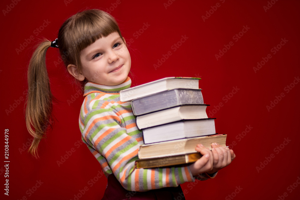 Little girl hold many books isolated on red. Concept of knowledge or school. Book lover Little girl hold many books isolated on red. Concept of knowledge or school. Book lover