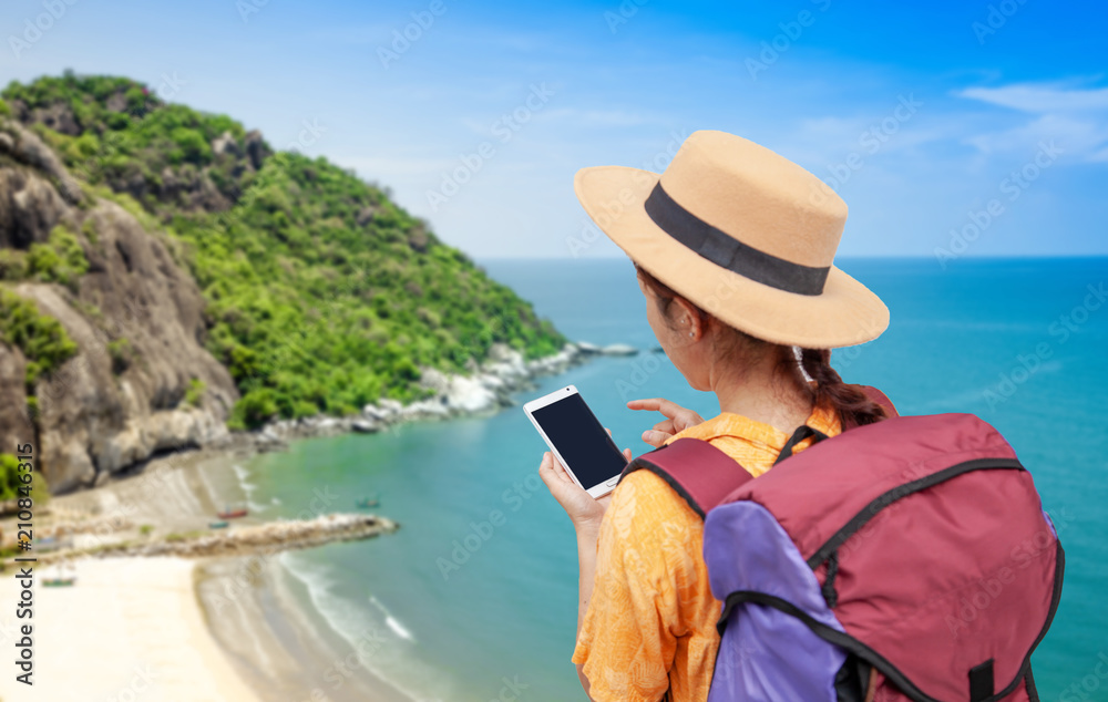 Search for apps and Navigation concept. Asian woman traveling backpacker hiker use smart phone and touching a mobile screen on mountain peak .