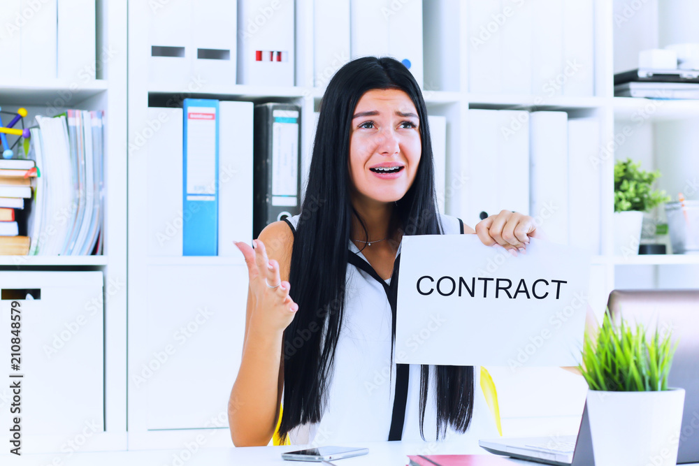 Young sad business woman ripping contract at the desk. Young sad business woman ripping contract at the desk.