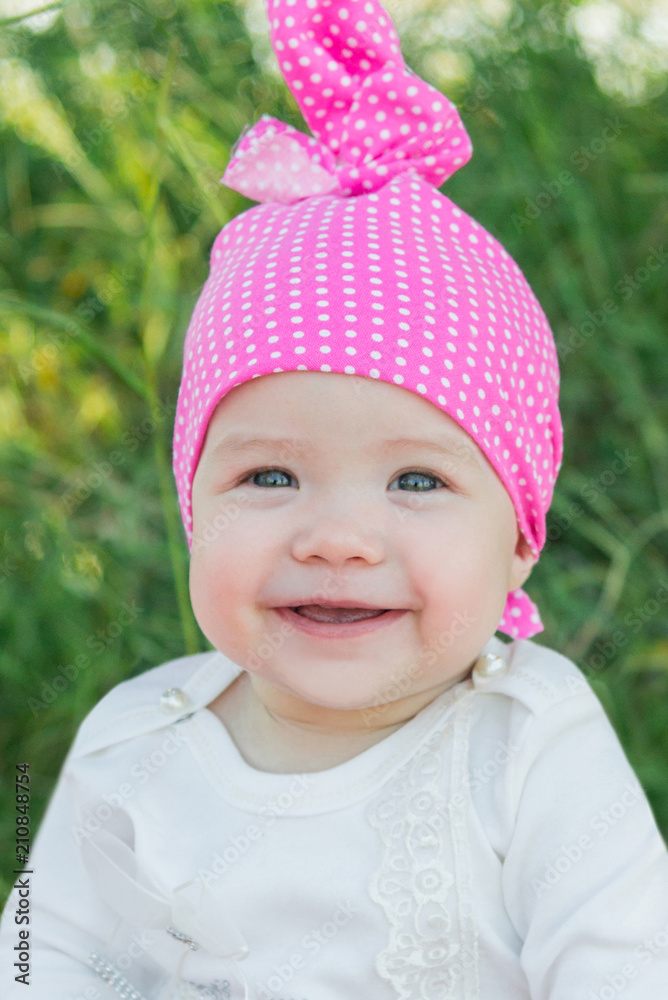 Smiling child in the grass. Hat in polka dots. Green grass. Smiling child. Smiling child in the grass. Hat in polka dots. Green grass. Smiling child.