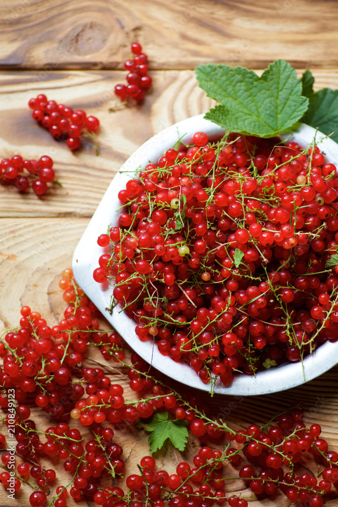 Red juicy currant lies on a wooden table and in plate. Red juicy currant lies on a wooden table and in plate.