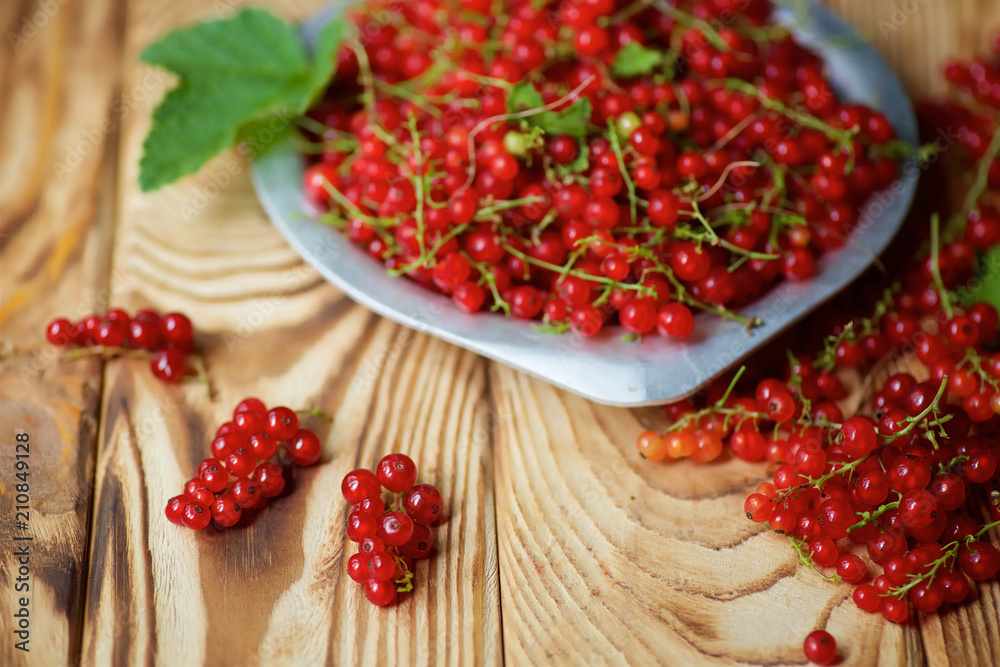 Red juicy currant lies on a wooden table and in plate. Red juicy currant lies on a wooden table and in plate.