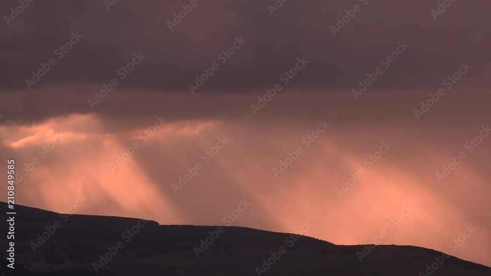 Time lapse of sunset sun rays through the clouds. Mountain silhouette. Heavy clouds in the background. Spectacular sunset rays Time lapse of sunset sun rays through the clouds. Mountain silhouette. Heavy clouds in the background. Spectacular sunset rays