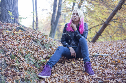 Beautiful blonde woman sitting on concrete stairs in autumn park, 