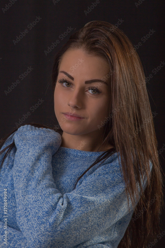 Studio portrait of beautiful young woman wearing blue sweater posing hugging herself Studio portrait of beautiful young woman wearing blue sweater posing hugging herself