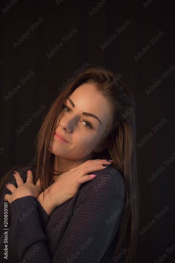 Beautiful young girl wearing sweater posing on black studio background touching her head with hand Beautiful young girl wearing sweater posing on black studio background touching her head with hand