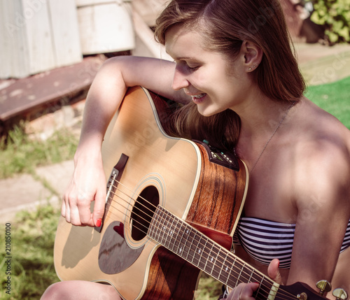 Woman singing and playing on guitar outdoors