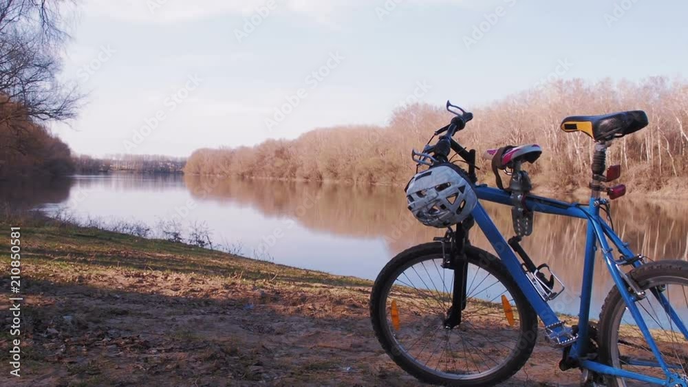 A bicycle on the nature by the river. The child walks by the river.