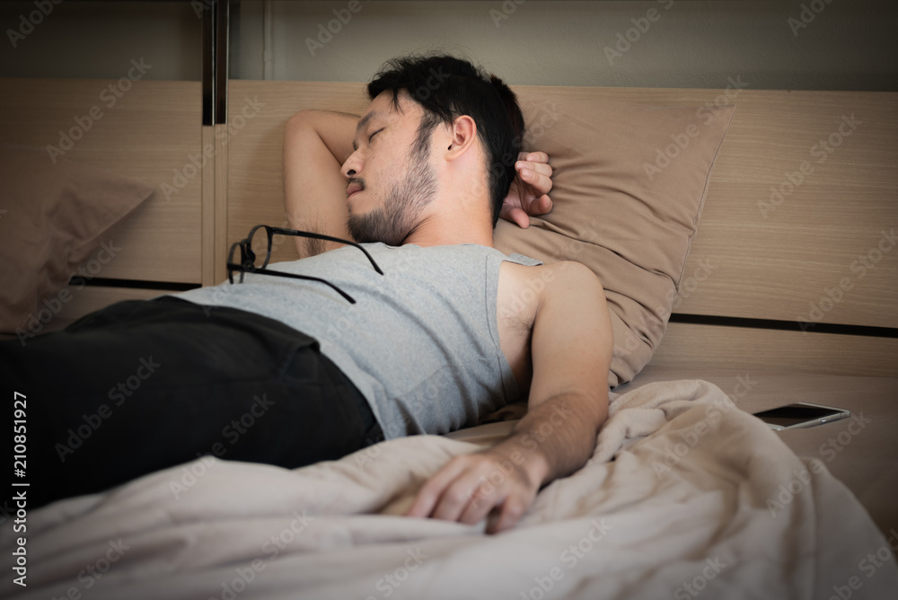 Young asian man sleeping on the bed at night.