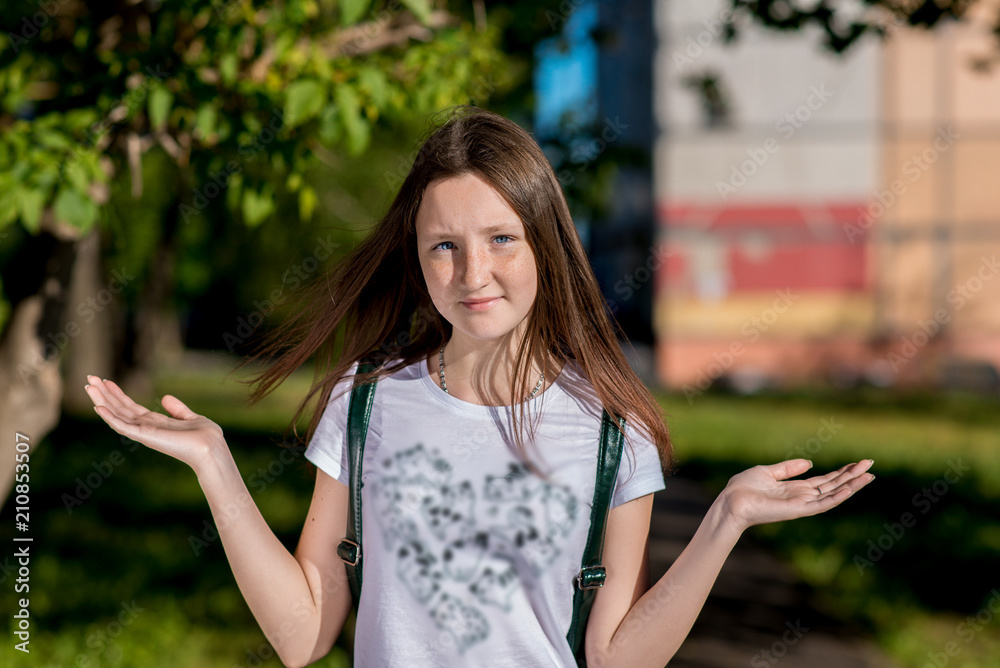 Beautiful schoolgirl girl. In the summer in the park after school. He raises his hands to sides. The concept of weights is the choice of action. Emotion choice decision. Beautiful schoolgirl girl. In the summer in the park after school. He raises his hands to sides. The concept of weights is the choice of action. Emotion choice decision.