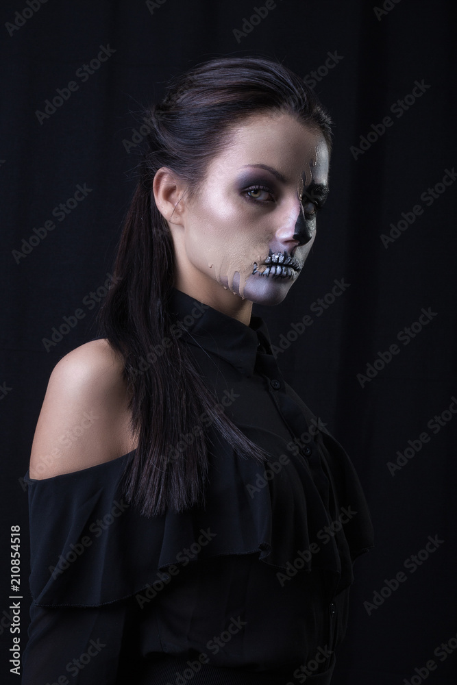 Studio portrait of brunette woman with scary paint on face posing on black background Studio portrait of brunette woman with scary paint on face posing on black background