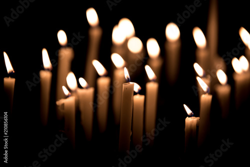 Many burning candles - Light of candels in the church on the black background