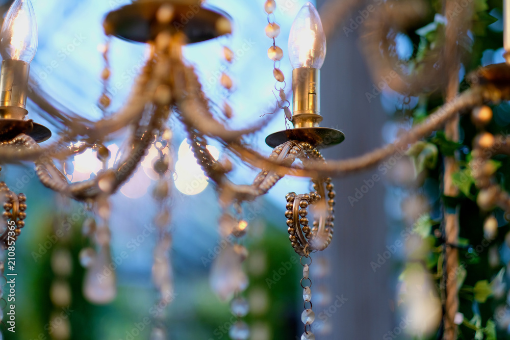 Electric lamps in the form of candles on a chandelier of yellow metal with pendants Electric lamps in the form of candles on a chandelier of yellow metal with pendants