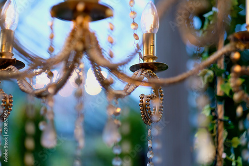 Electric lamps in the form of candles on a chandelier of yellow metal with pendants © Anna Jurkovska