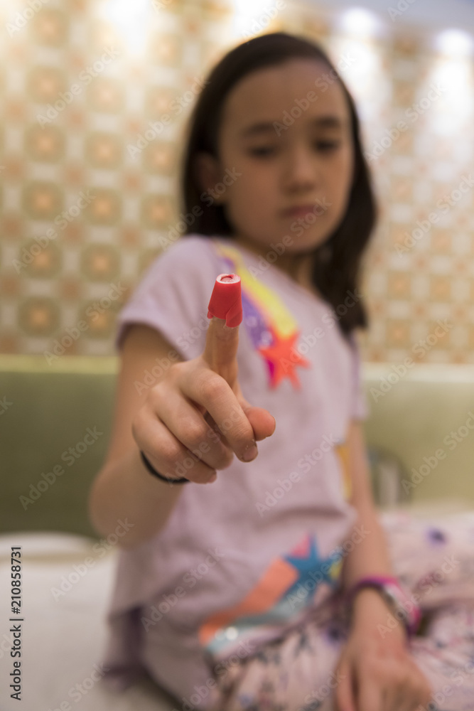 Sad girl shows her bandaid covered finger in the doctor's office Sad girl shows her bandaid covered finger in the doctor's office