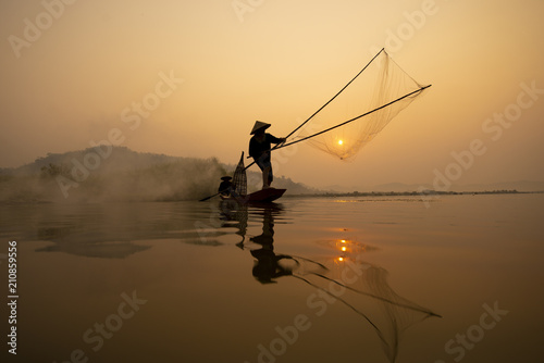 Fisherman is fishing in the river while sunset.