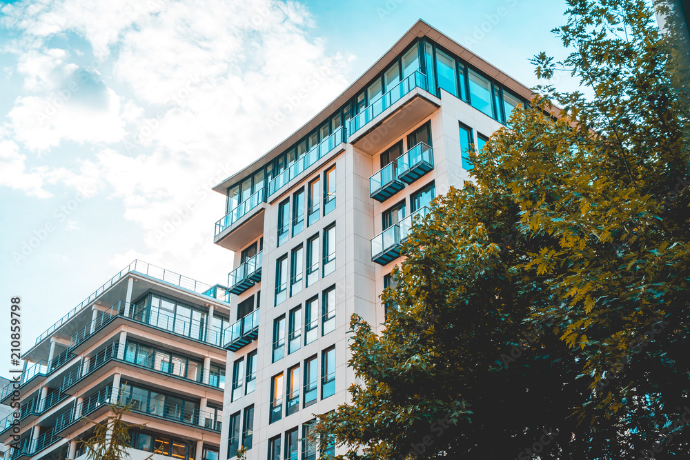 Obraz premium white and orange colored finance houses with green tree in the frontside