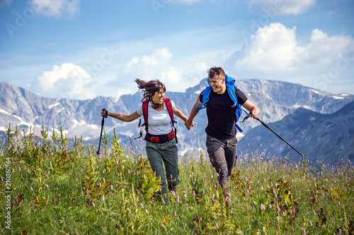 Shot of happy young couple of hikers running in mountain field