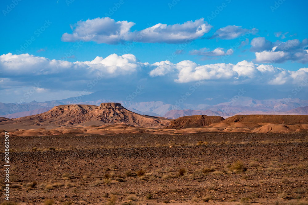 African landscape of Atlas mountain in Sahara desert with bright blue sky and clouds