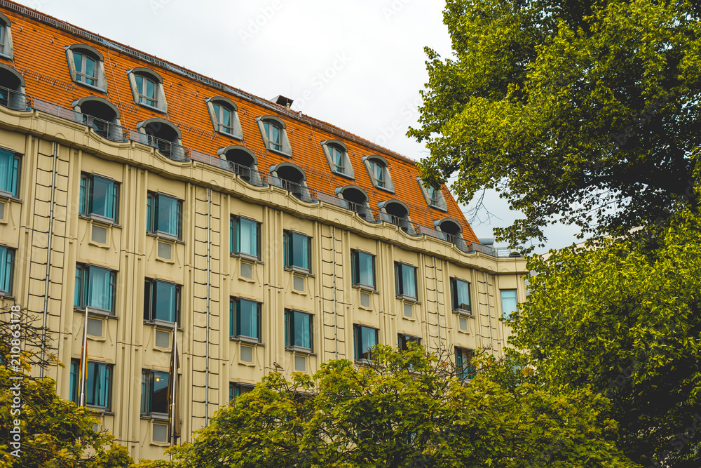 Fototapeta premium residential building with red rooftop framed by a tree