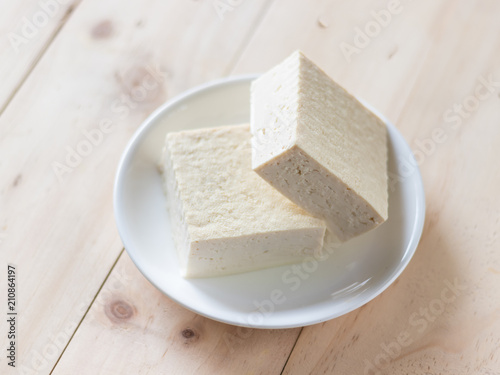 Tofu made from soybean on white plate over wooden background