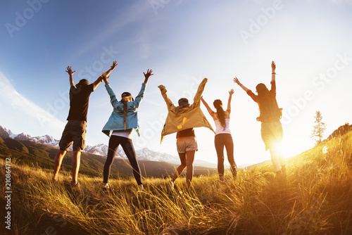 Group happy friends mountains sunset raised arms