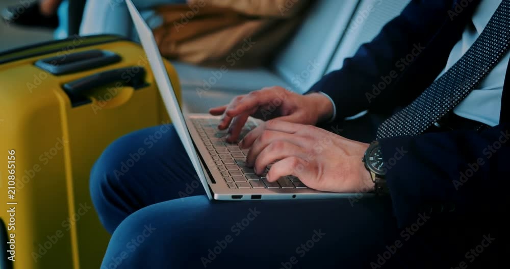 Businessman typing on laptop while sitting in airport waiting room