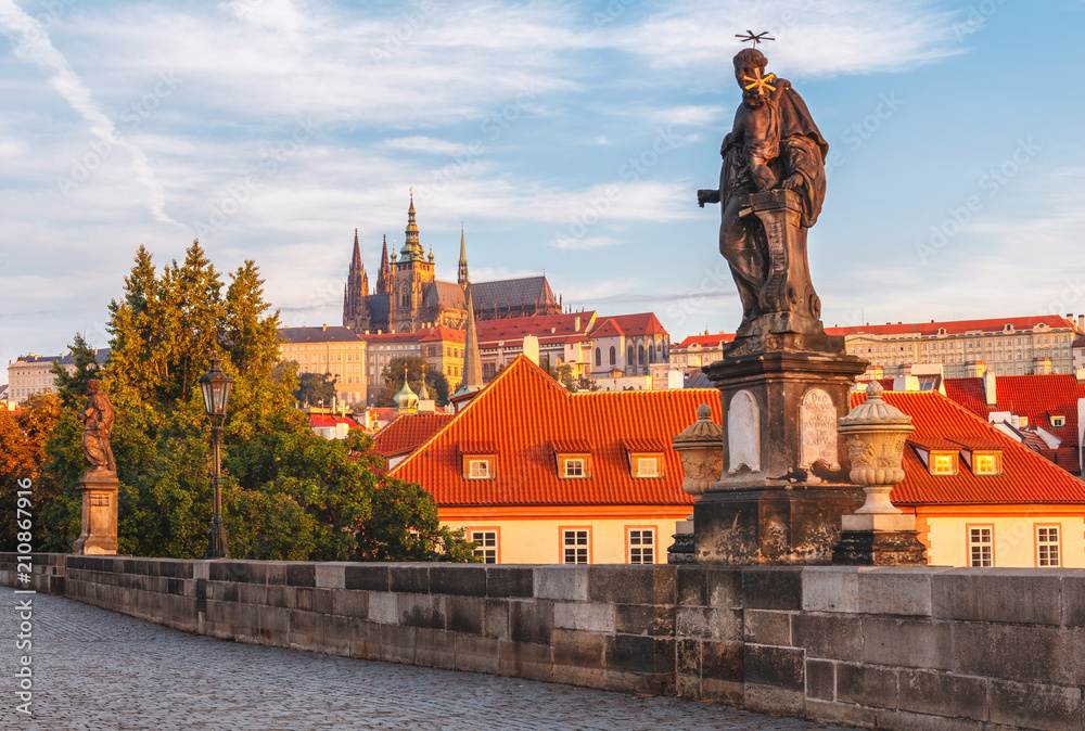 Prague castle in the early morning from Charles bridge with beautiful statue on the foreground. Prague, Czech Republic