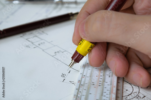 Man holding technical pen and working on a hand drawn technical drawing.