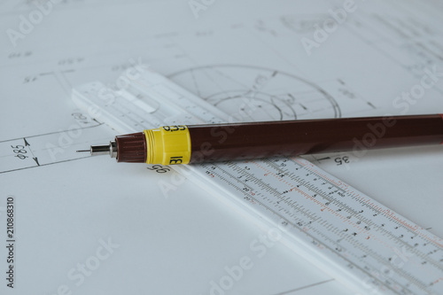 Technical pen (rapidograph) on slide rule and technical drawing. Engineer equipment.