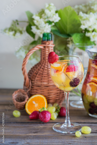 Homemade refreshing fruit sangria or punch with champagne, strawberries, oranges and grapes.