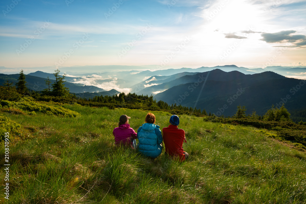 Friends, travelers relax on the green mountain meadow