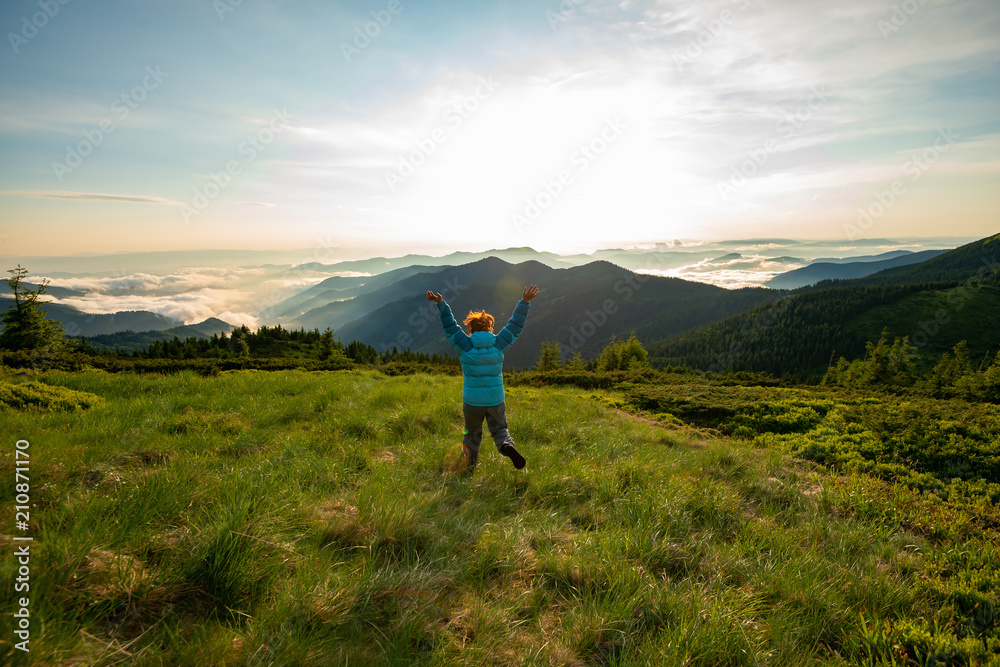 Happy traveler, female running along the green meadow