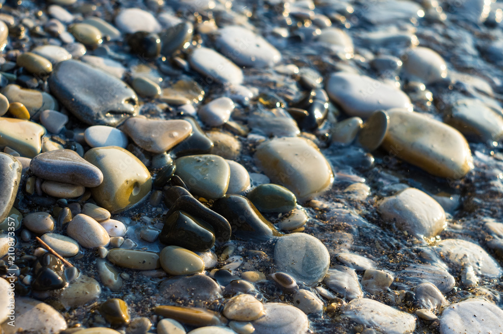 pebble stones on the sea beach, the rolling waves of the sea with foam