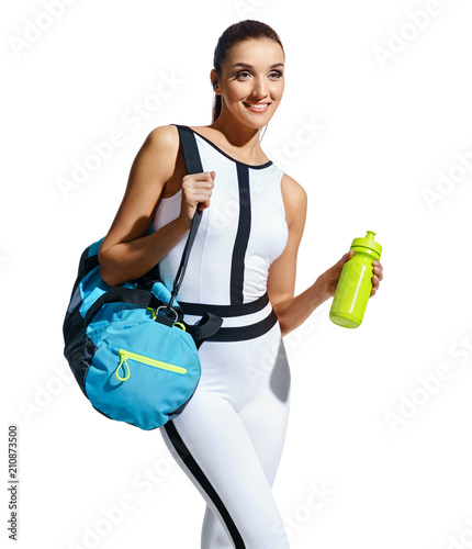Go to gym! Smiling sporty woman in fashionable sportswear with sports bag and shaker on white background. Sports and healthy lifestyle