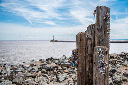 Bundles of locks on a beach by the lake with a lighthouse in the background photo