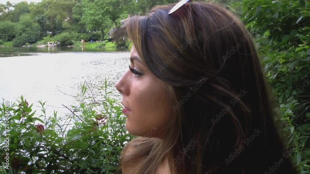Close Up Of A Young Caucasian Woman With Long Brunette Hair Sitting Quietly and Contemplatively By A Pond Close Up Of A Young Caucasian Woman With Long Brunette Hair Sitting Quietly and Contemplatively By A Pond