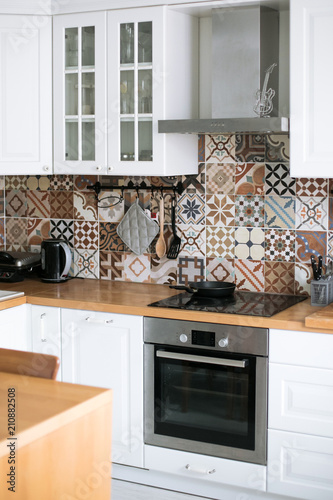 Beautiful stylish white real kitchen in Scandinavian style with wooden top and Spanish tiles