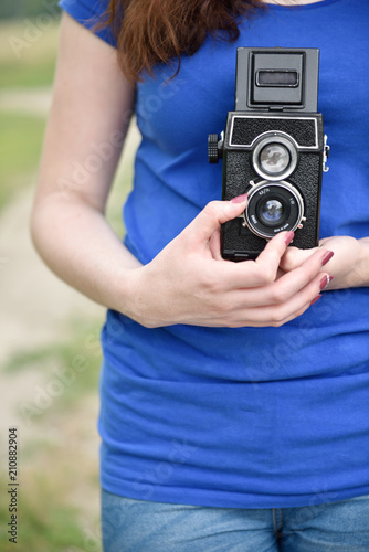 Casual girl taking picture with vintage twin-lens reflex camera