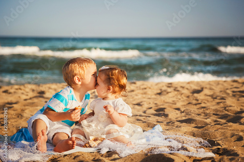 Small kids are kissing and having fun at beach together near the