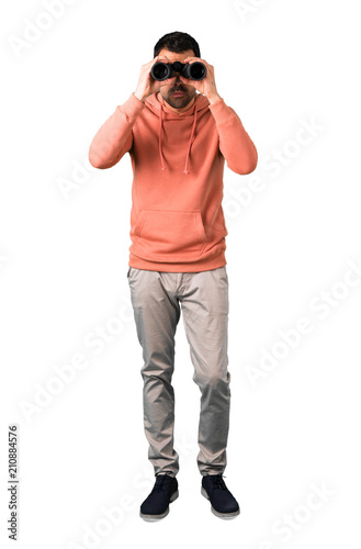 Full body of Man in a pink sweatshirt and looking for something in the distance on isolated white background