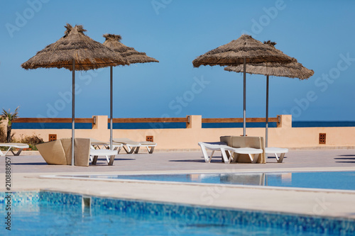 Outdoor swimming pool with sun umbrellas, blue sky. photo
