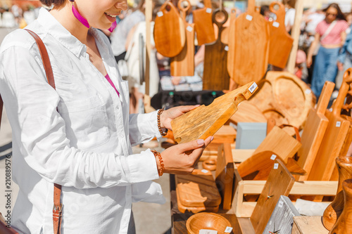 Woman choosing a cutting board in the outdoor flea handmade market