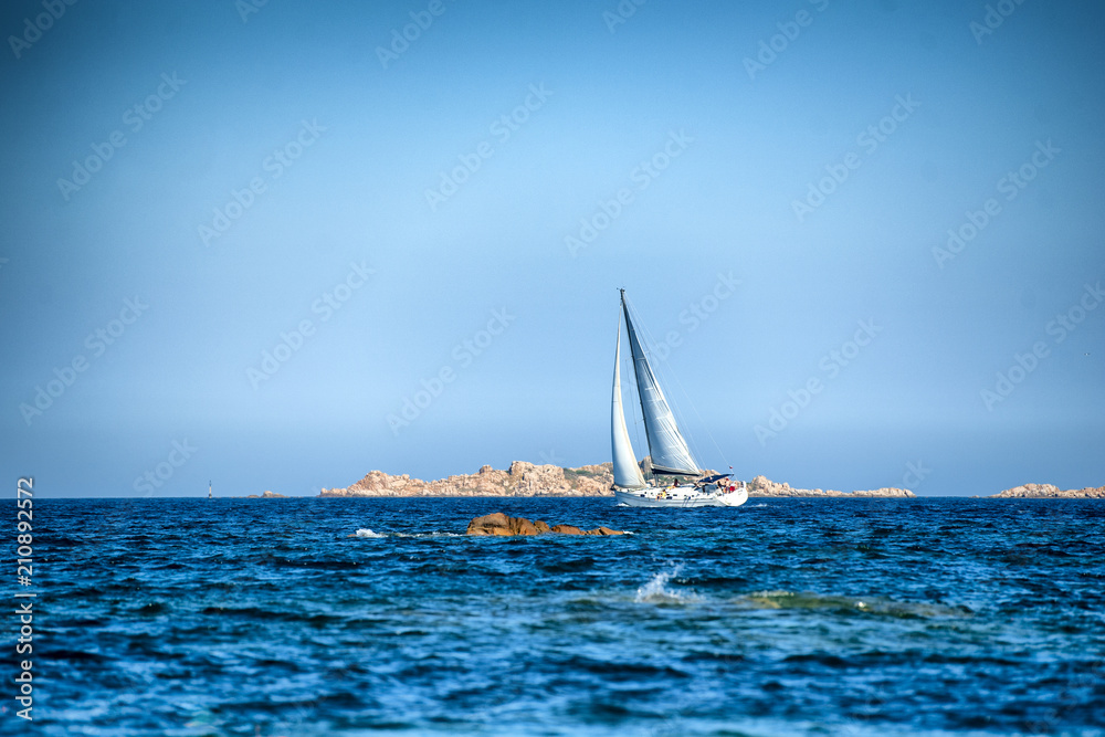 On a sunny summer day a white sailboat whit spinnaker open  sail on  Mediterranean Sea in Sardinia, luxury vacations