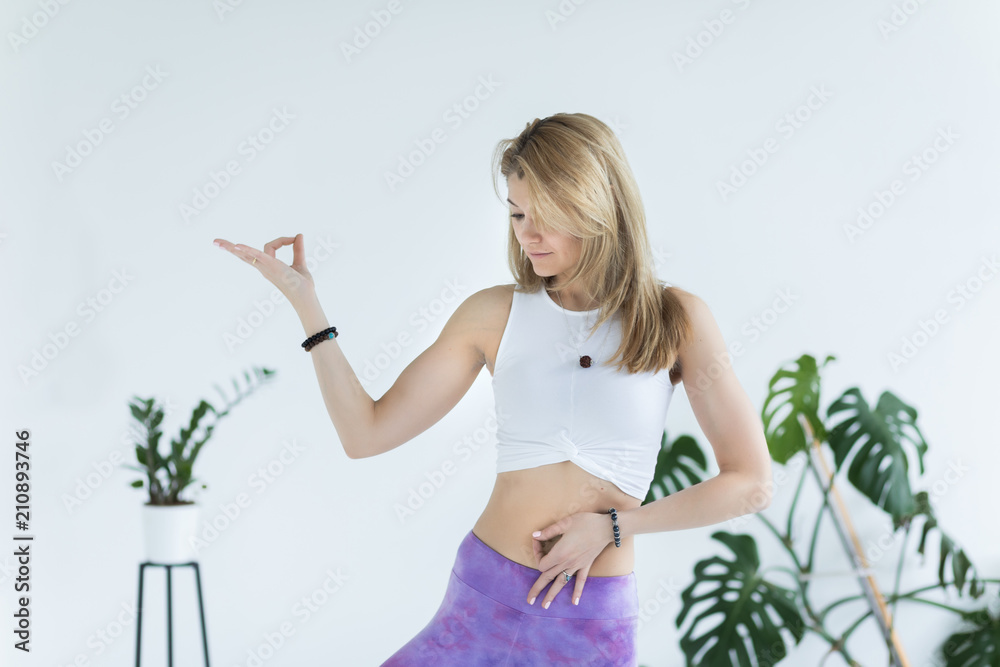 Portrait of Woman holding hands in yoga mudra together as meditation prayer on white background with tropical flowers. Yoga concept. Portrait of Woman holding hands in yoga mudra together as meditation prayer on white background with tropical flowers. Yoga concept.
