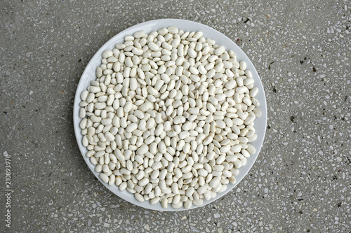 white beans on a plate on granite background